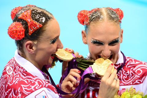 Russia's Natalia Ishchenko and Svetlana Romashina bite their medals after winning gold in the duets free routine final during the synchronized swimming competition at the London 2012 Olympic Games.