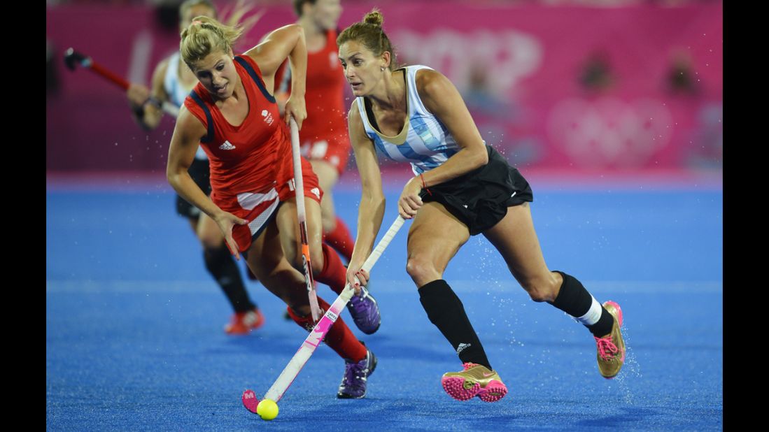 Argentina's Luciana Aymar, right, rushes past Britain's Georgie Twigg, in the women's hockey semifinal.
