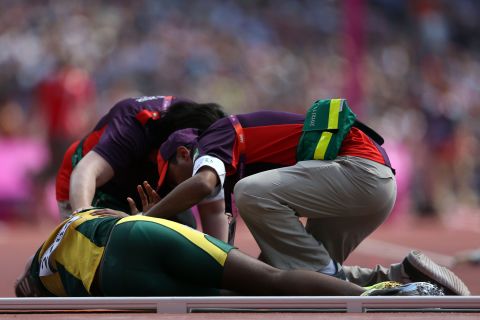 Ofentse Mogawane of South Africa receives assitance after colliding with a Kenyan runner during the men's 4 x 400-meter relay round 1 heats.