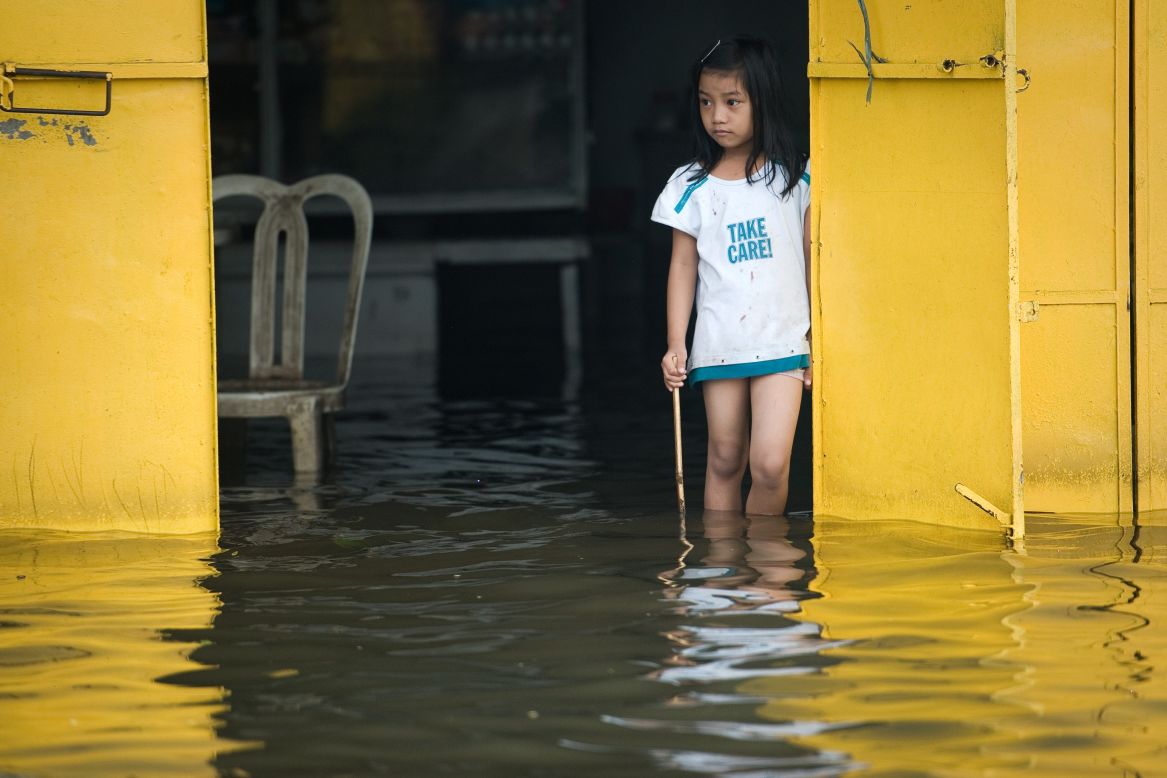A girl eyes floodwaters Friday from a restaurant in Apalit outside Manila. 