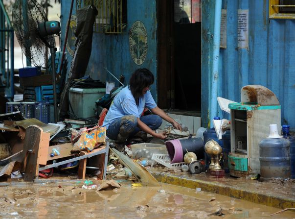 A resident cleans her mud-stained belongings Friday in suburban Manila. The weather has affected more than 2.4 million people, officials said.