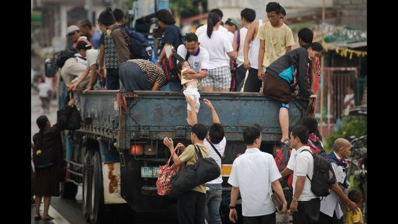Filipinos step down from a truck Friday after crossing through floodwaters in Apalit outside Manila.