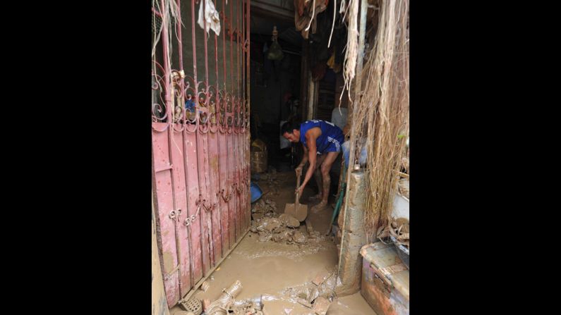 A resident shovels mud from his house Friday in the village of Tumana.
