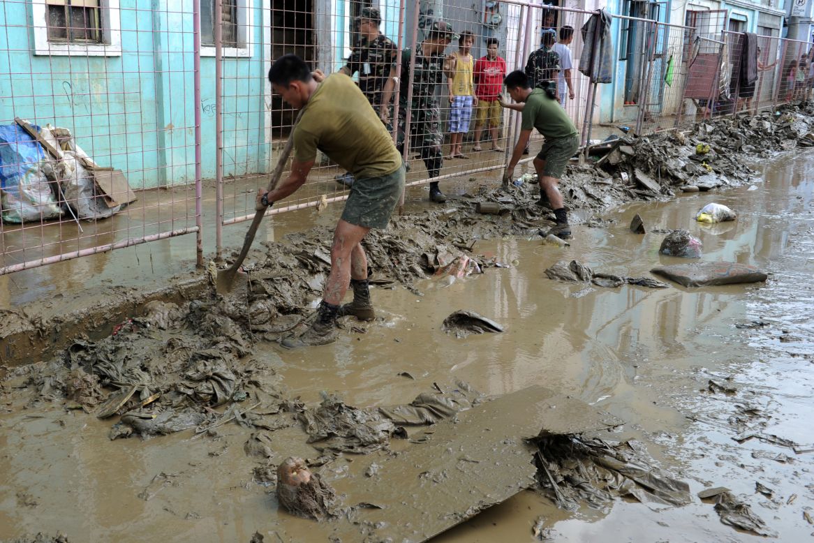 Philippine army corp engineers help residents clean streets Friday in a Manila suburb. It may take weeks for waters to recede in the lower-lying areas, forecasters say.