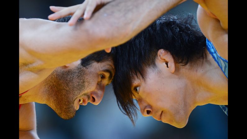 Azerbaijan's Ashraf Aliyev, left, grapples with Sohsuke Takatani of Japan in the men's freestyle 74-kilogram wrestling.