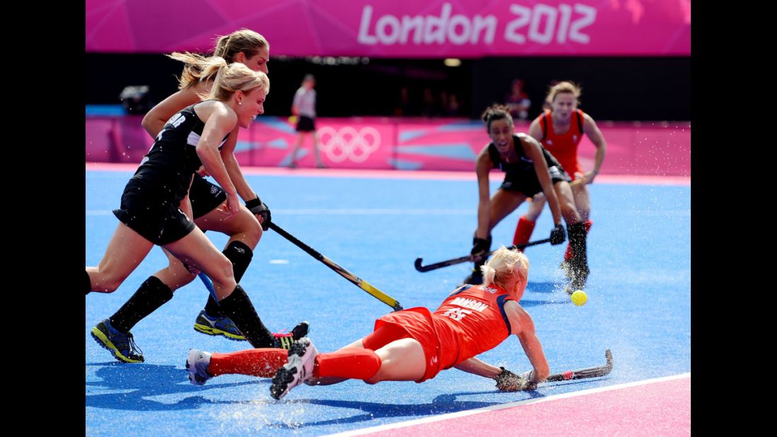 No. 15 Alex Danson of Great Britain, right, battles for the ball against No. 2 Emily Naylor, front, and Clarissa Eshuis No. 16 of New Zealand during the first half of the women's hockey bronze medal match.