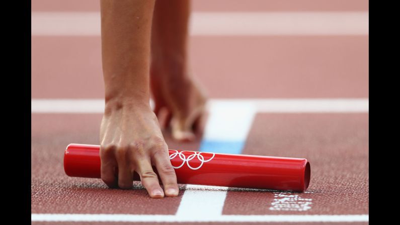 An athlete holds the baton during the women's 4 x 400-meter relay round 1 heats.