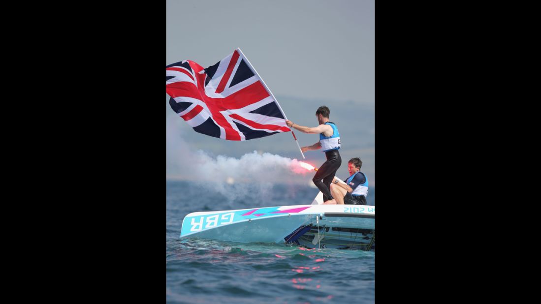 Luke Patience, left, and Stuart Bithell, right, of Great Britain let off flares as they celebrate finishing second and winning the silver medal in the men's 470 sailing.