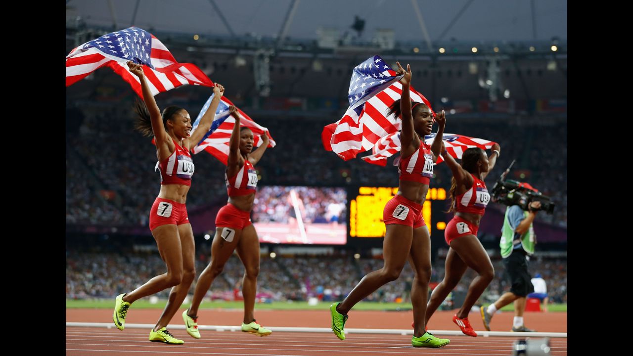 The U.S. women's 4x100-meter relay team wave the flag to celebrate their world record and gold medal winning victory.
