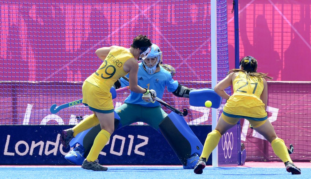 China's Zhang Yimeng, center, saves a shot from Australian Teneal Attard, left, as Attard's teammate Jayde Taylor stands by during the women's field hockey classification match.