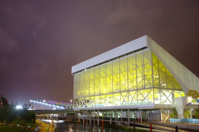 The Aquatic Centre with the Water Polo Arena in the background. From this angle, the Arena almost looked like a blue whale rising up from the Lea. The lights in its roof pulsed from blue to green to purple. 