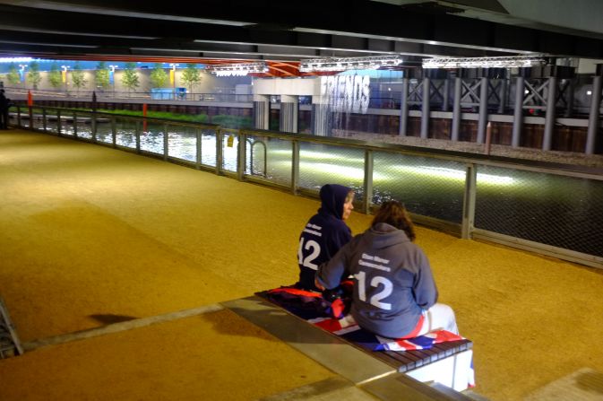 Two Eton Manor volunteers took a moment for a quiet conversation in front of the "bit.fall" installation by artist Julius Popp. Words taken from live news headlines are projected at random onto five man-made waterfalls under the Stratford Gate bridge.