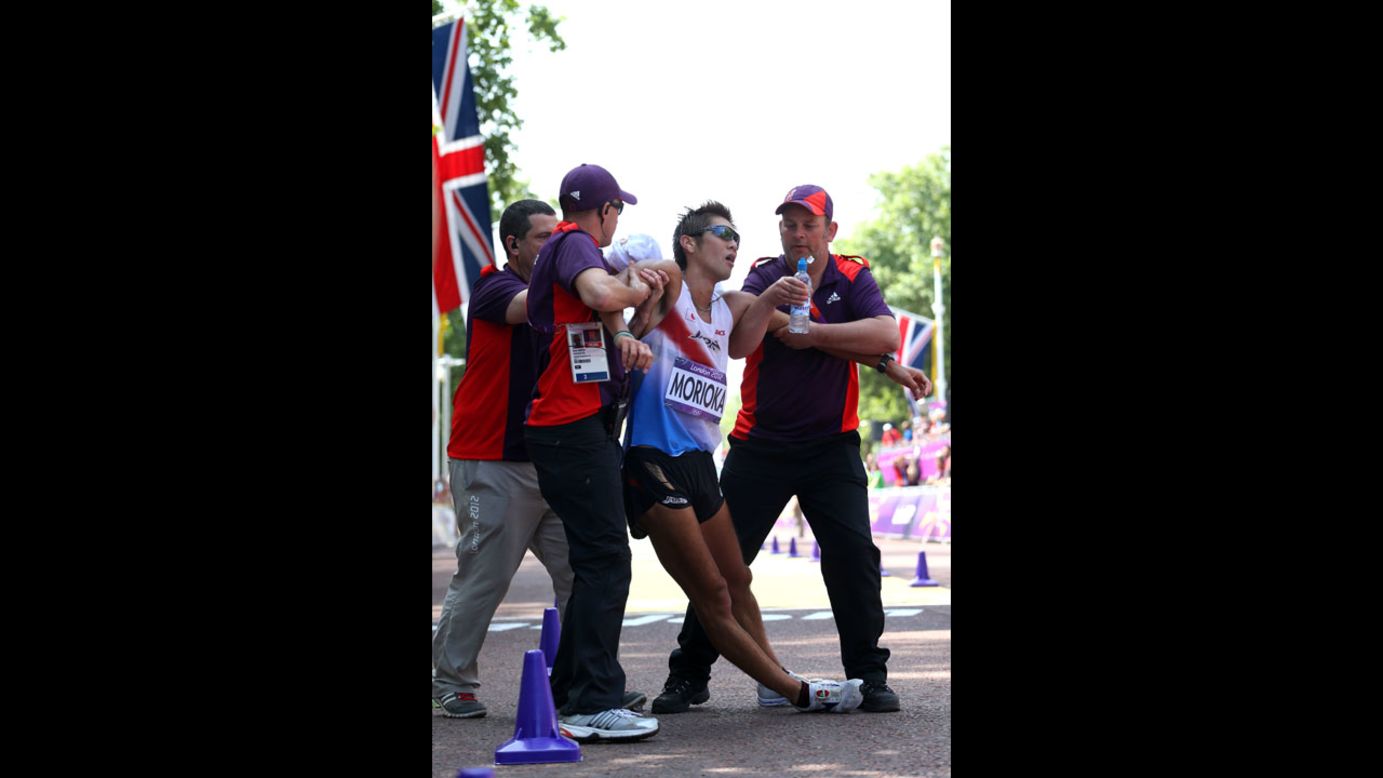 Japan's Koichiro Morioka gets assistance as he crosses the finish line during the men's 50-kilometer walk.