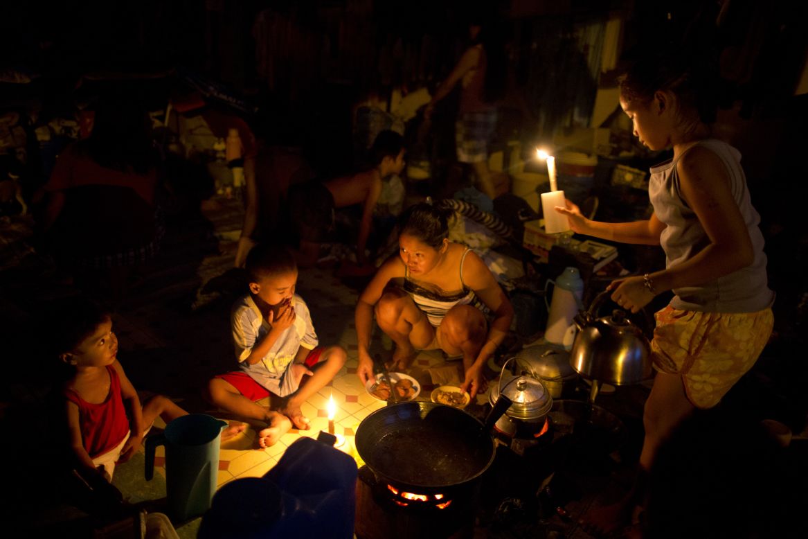 Flood victims use candles for light as they cook dinner at a crowded evacuation center on Saturday, August 11, in Manila, Philippines.