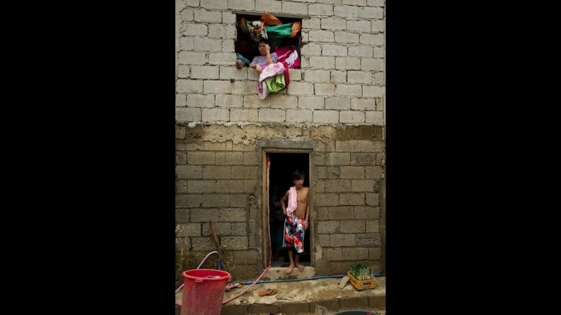 Residents of the Tomana slum in the Manila suburb of Marikina stand inside their home after water finally recedes. 