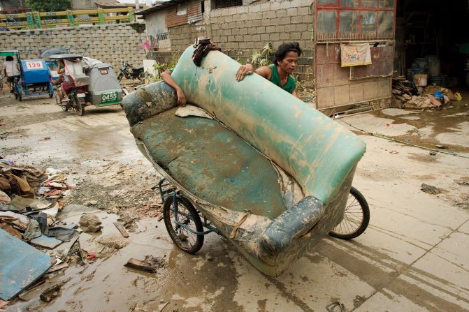 A man uses a bicycle to transport a sofa chair in Tomana slum following floods that submerged 80% of Manila.
