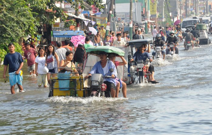 Residents commute Saturday along a flooded stretch of road in Calumpit.
