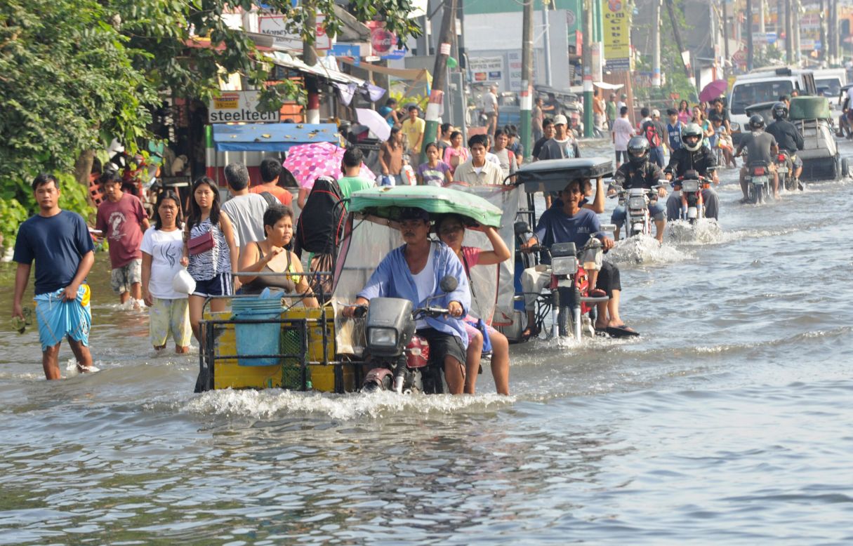 Residents commute Saturday along a flooded stretch of road in Calumpit.
