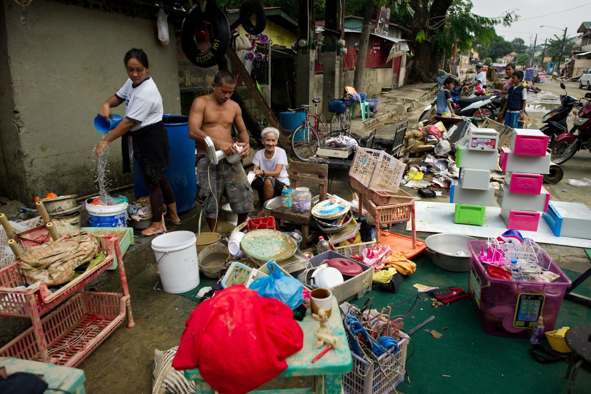 Flood victims clean their goods outside their house after water receded from their homes in the river bank slum.