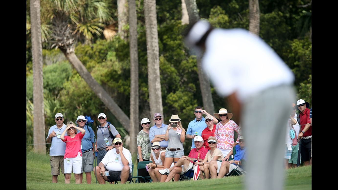 Spectators look on as Bubba Watson putts on the first green.
