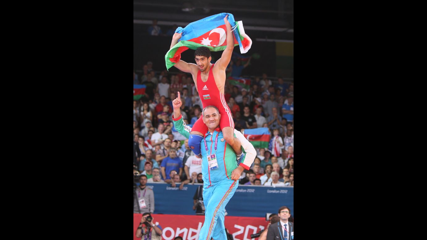 Azerbaijan's Toghrul Asgarov celebrates with his coach after defeating Russia's Besik Kudukhov in a men's freestyle wrestling gold medal match.