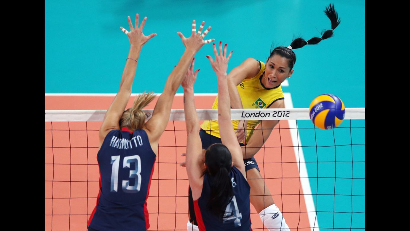 No. 8 Jaqueline Carvalho of Brazil spikes the ball against the United States' No. 13 Christa Harmotto and No. 4 Lindsey Berg during the women's volleyball gold medal match.