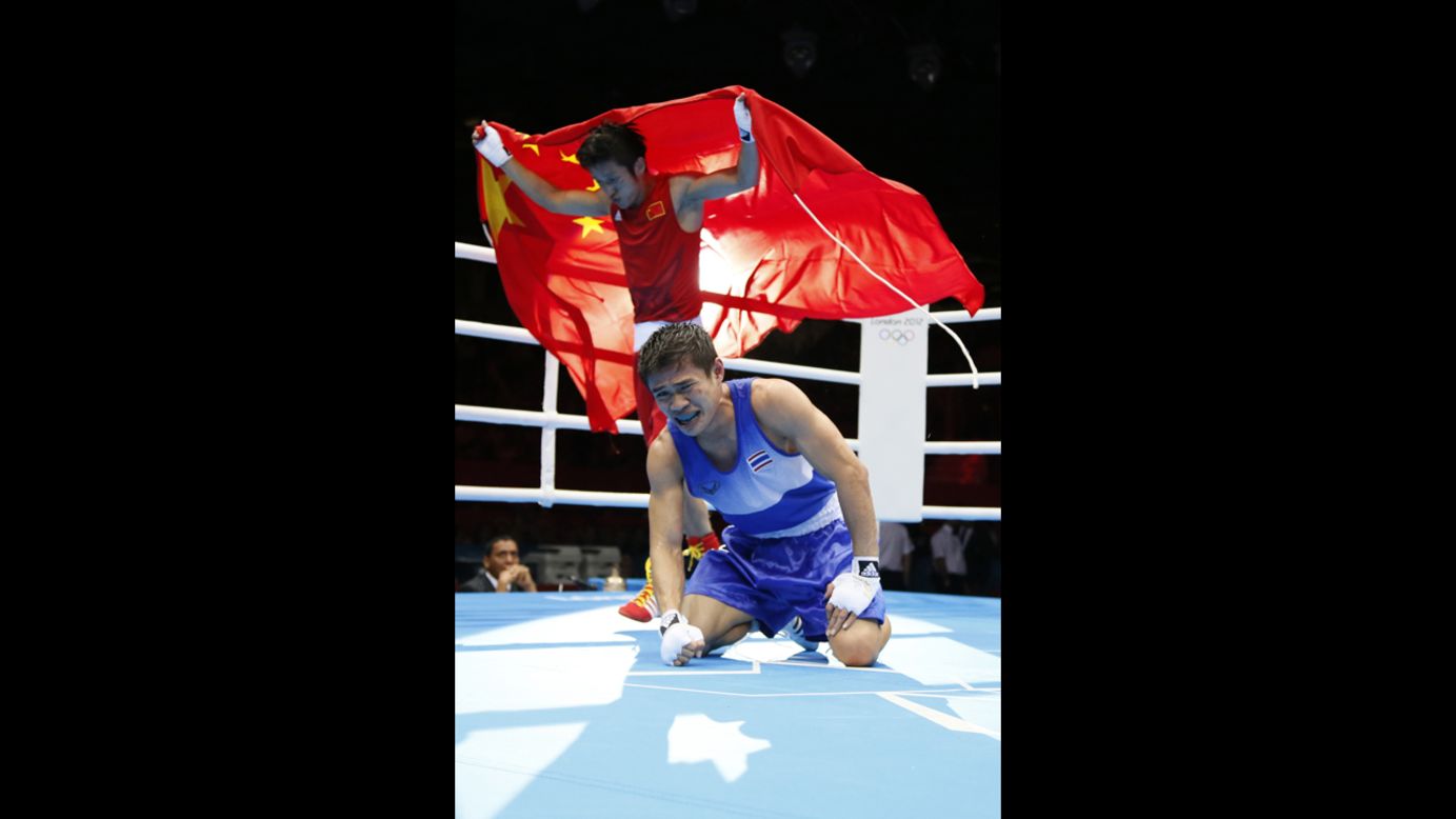 Kaeo Pongprayoon of Thailand, in blue, reacts as Shiming Zou of China waves the Chinese national flag after being declared winner in the light flyweight boxing final.