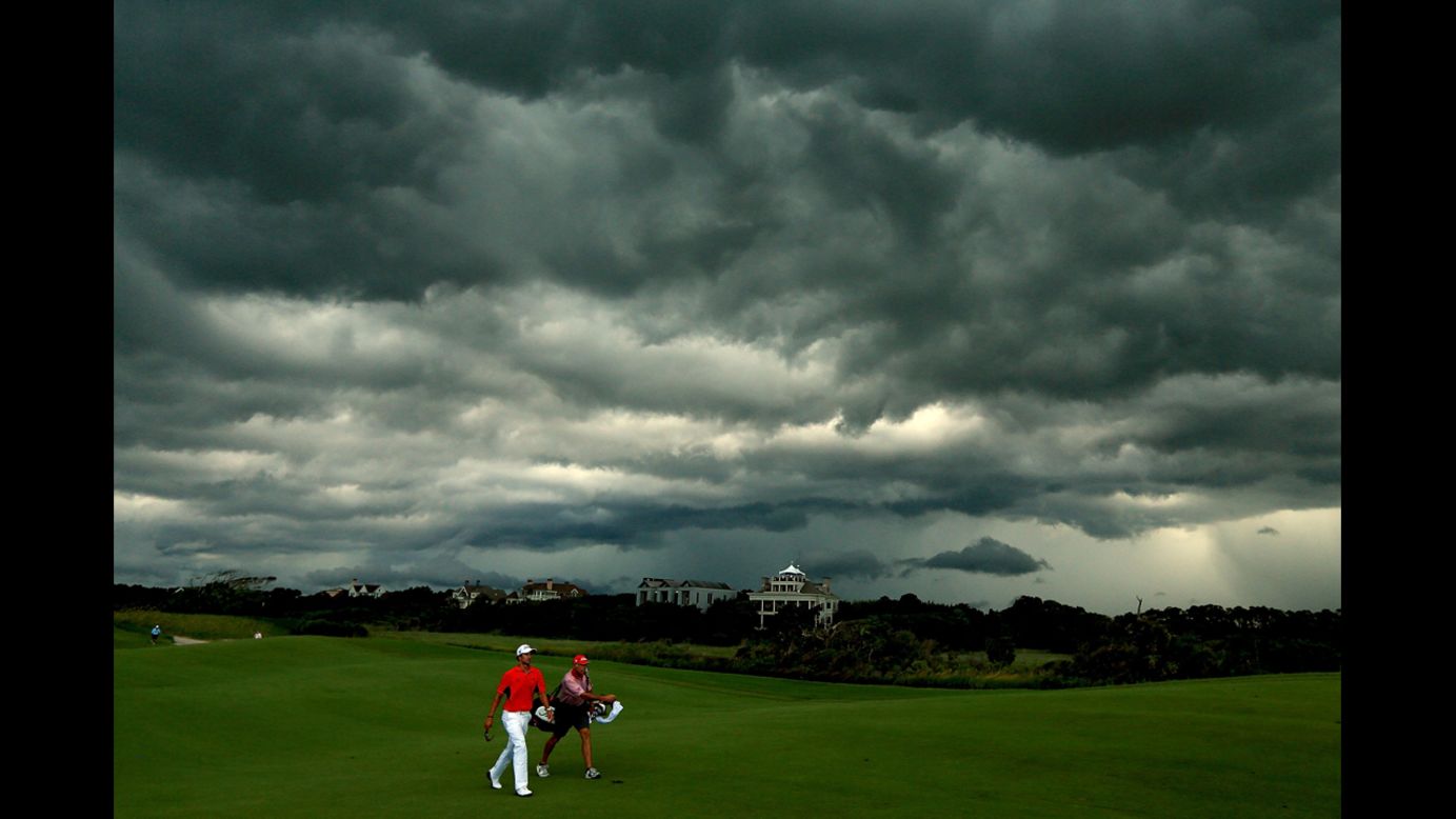 Adam Scott of Australia walks off the course under dark clouds as play is suspended due to rain on Saturday, August 11.