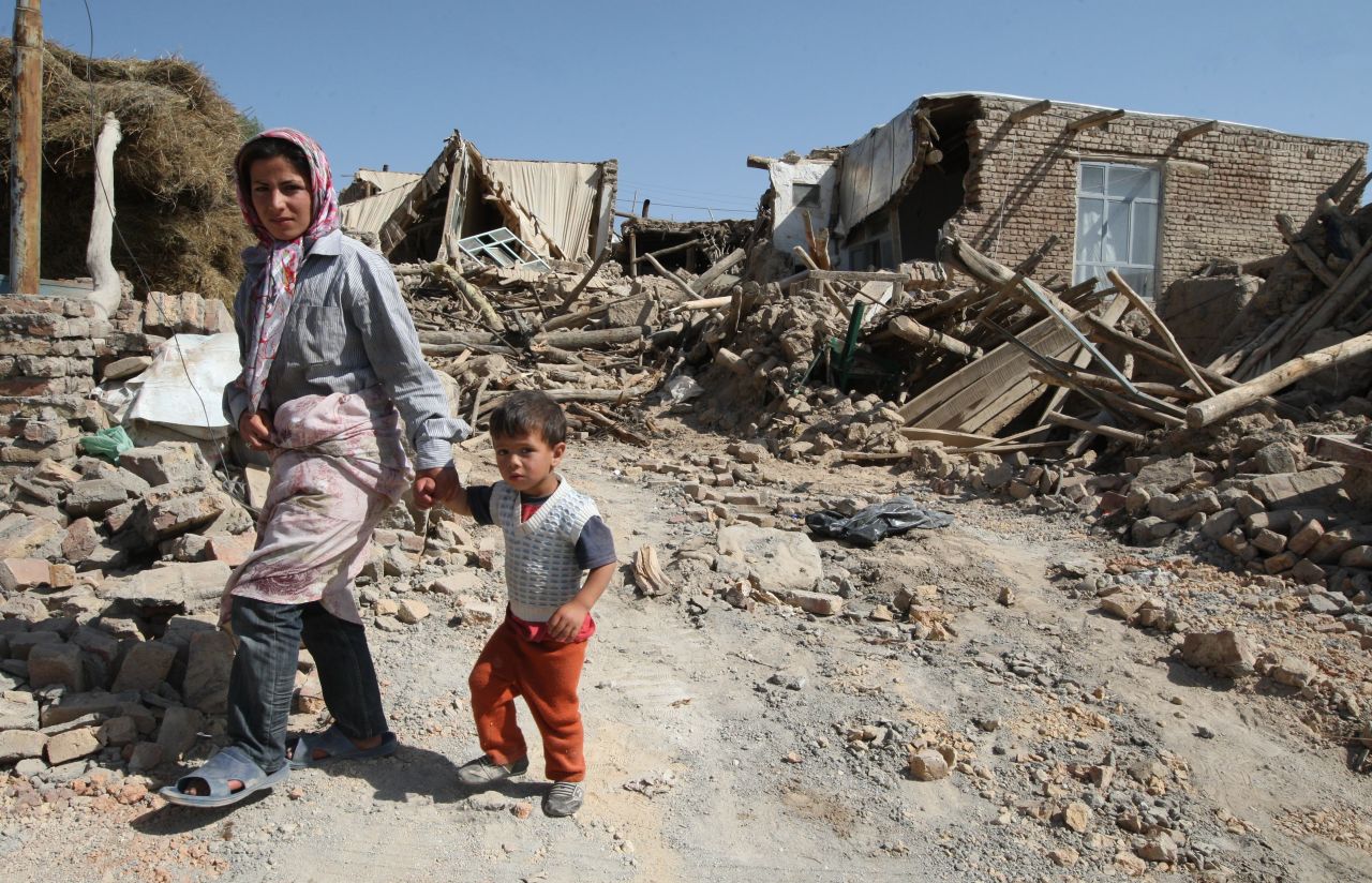 Residents walk among the rubble of destroyed buildings in the village of Amir-Ali Kandi.