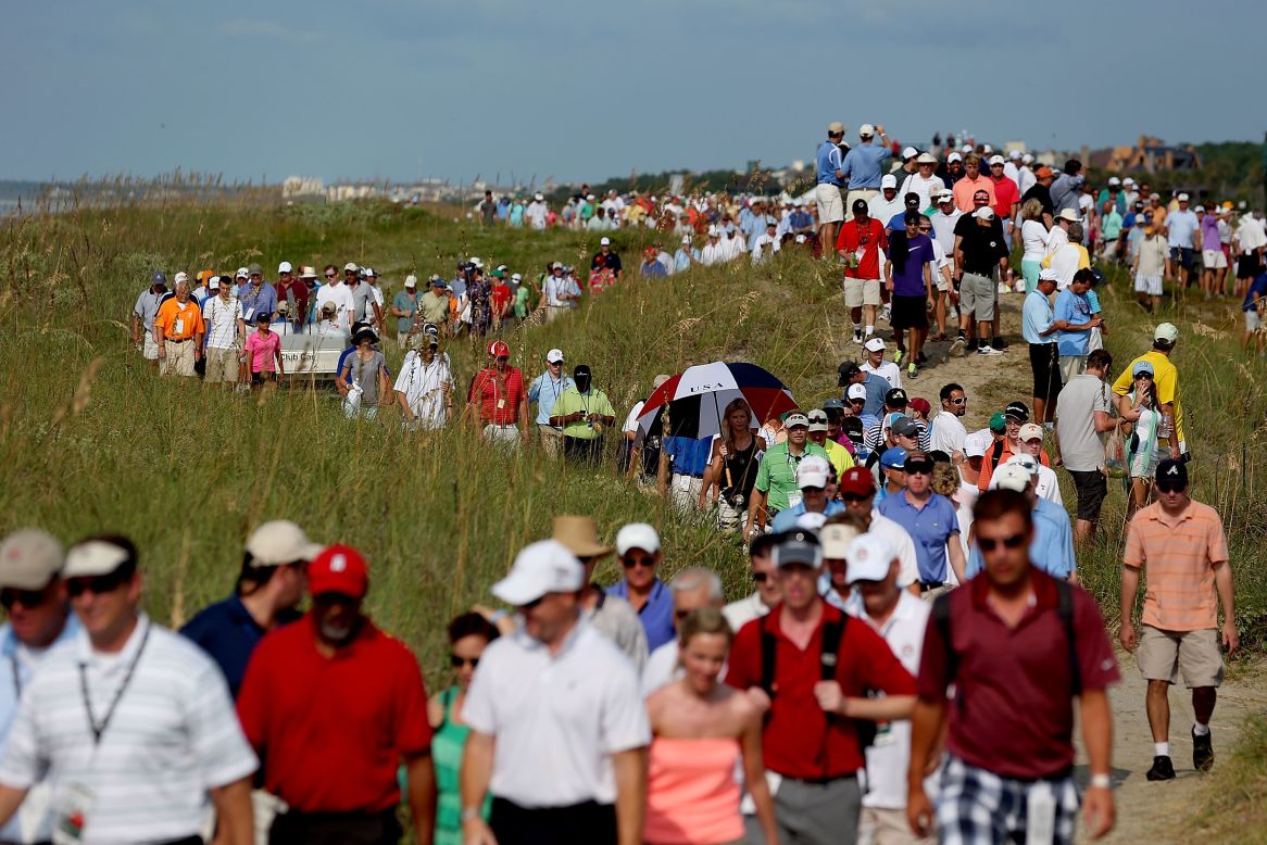 Spectators file along the course near the 16th hole to stake out a position for viewing.