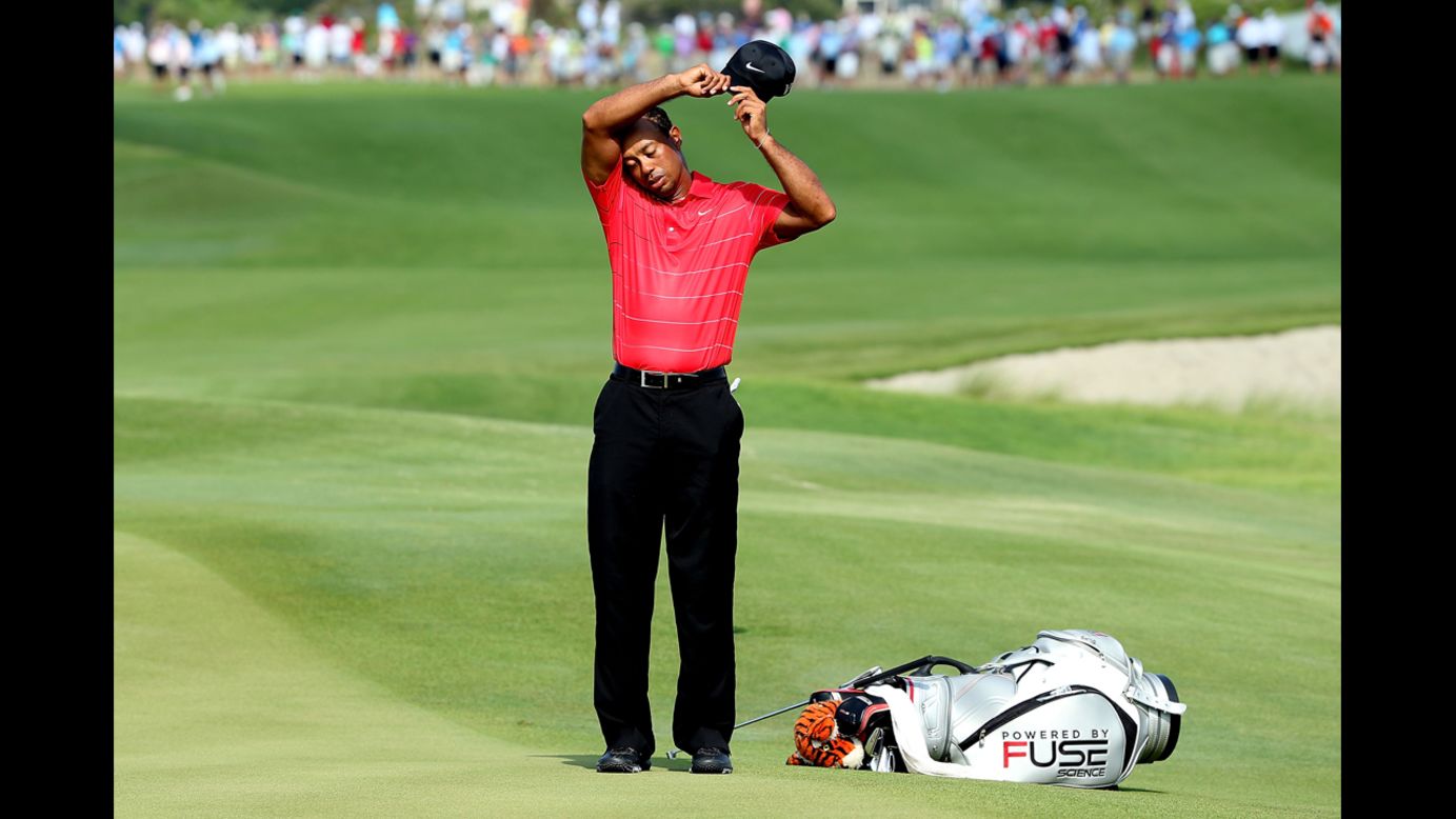 Woods, who finished the third round with a 74, wipes his brow between holes.