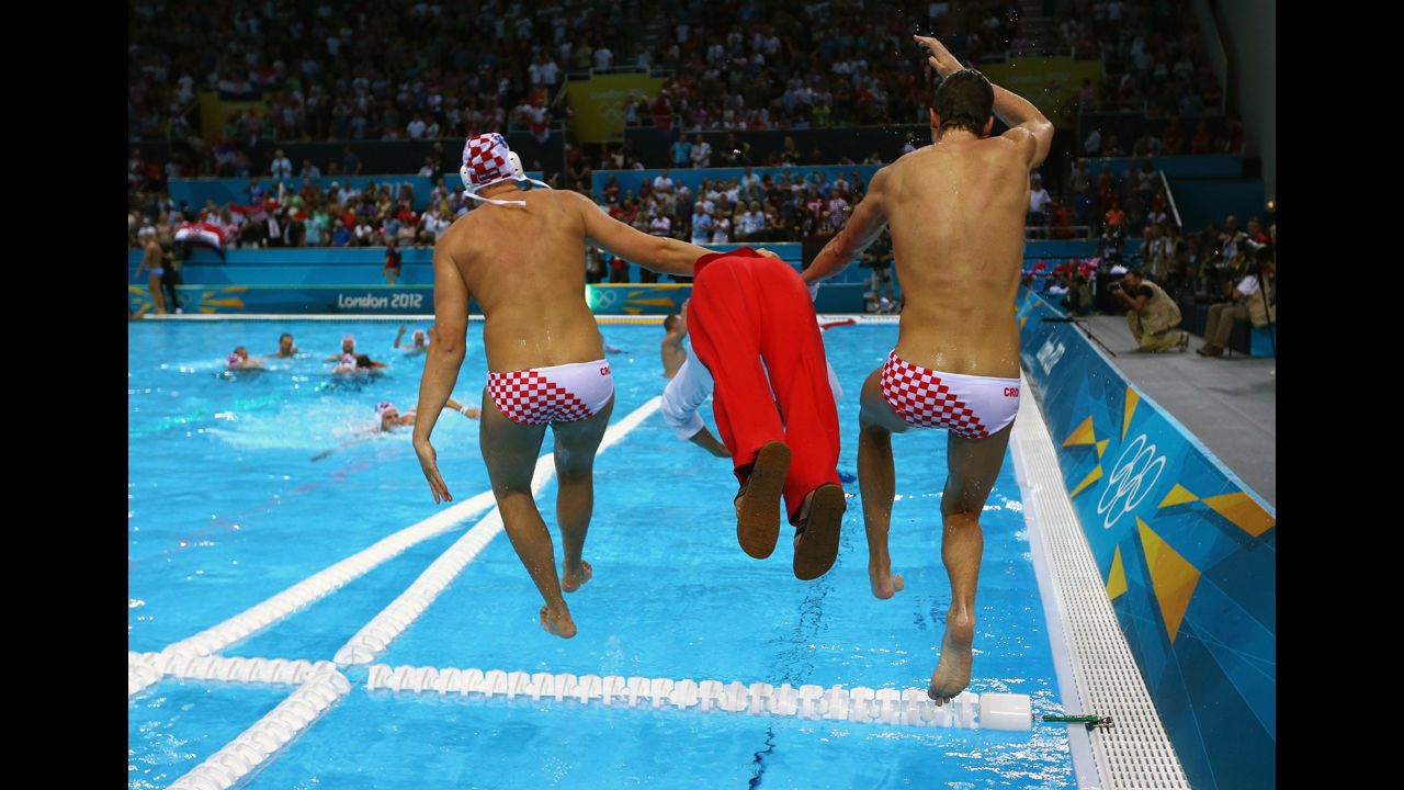 Two Croatian players and a member of the coaching staff jump into the pool after winning the gold medal in men's water polo.