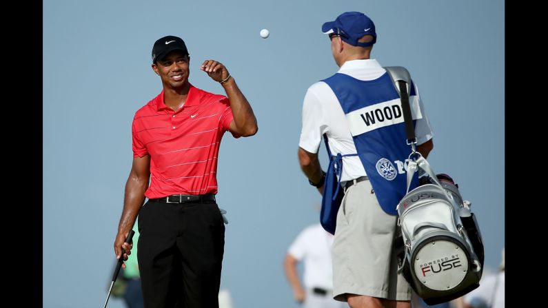 Woods catches a ball tossed by caddie Joe LaCava on the 14th green.
