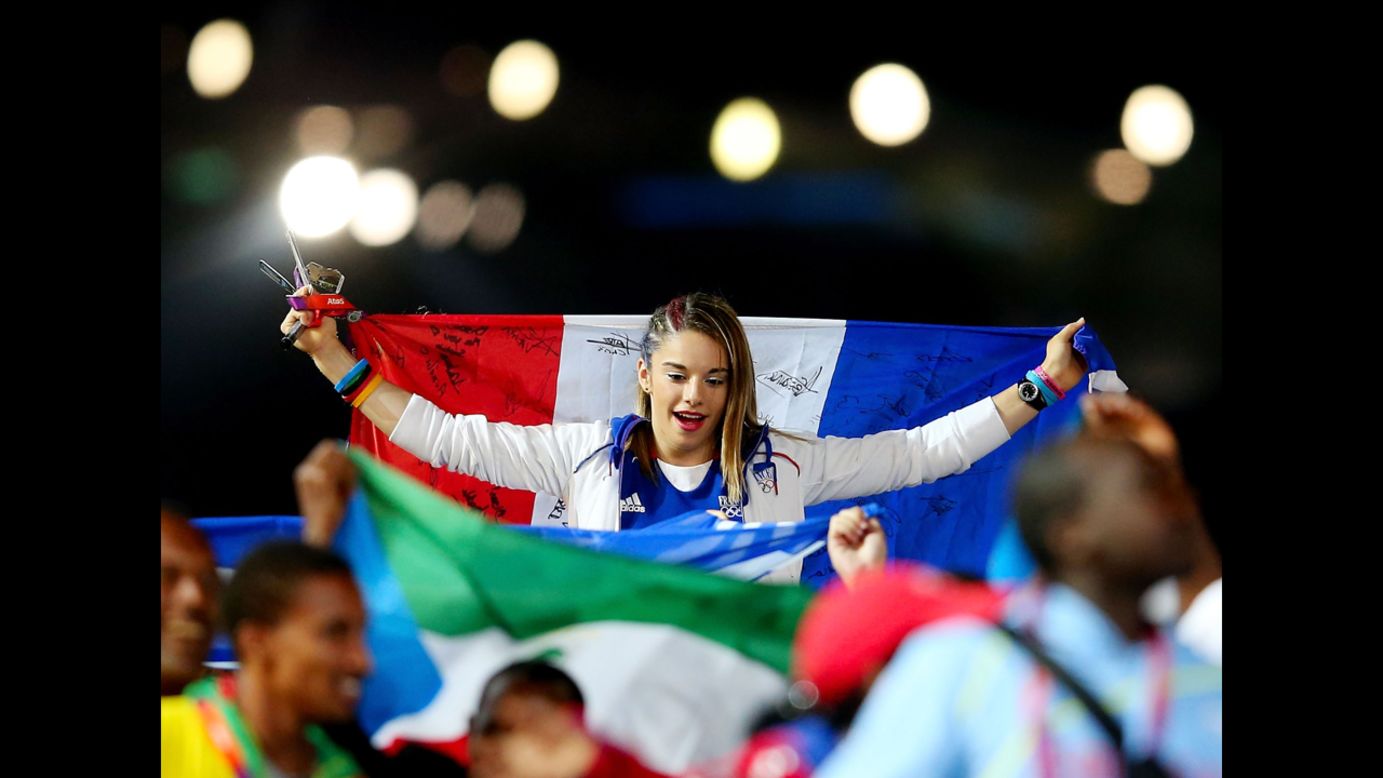 A  French athlete carries her nation's flag as the French team parades through the stadium.