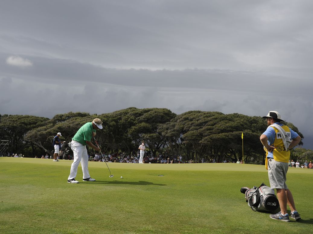Carl Pettersson of Sweden tries a putt from the edge of the green as storm clouds move in.