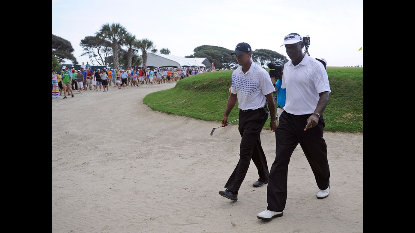 Tiger Woods, left, and Vijay Singh of Fiji walk off the course after the suspension of play.