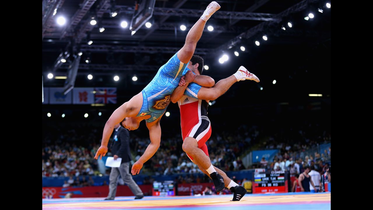 Takao Isokawa, in blue, of Japan is taken down by Magomed Musaev of Kyrgyzstan in the men's freestyle wrestling 96-kilogram eighth-final match. 