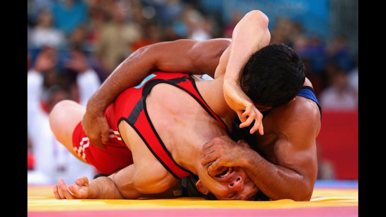 Sushil Kumar, in blue, of India battles with Akzhurek Tanatarov of Kazakhstan during the men's freestyle wrestling 66-kilogram semifinal match.