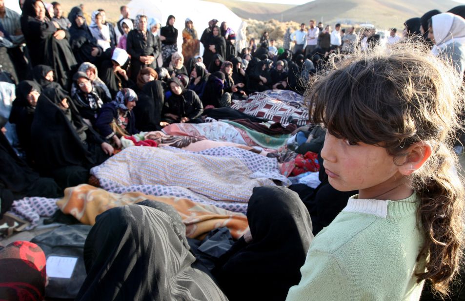 Iranians mourn over the covered bodies of loved ones in the village of Baje-Baj, Iran, on Sunday, August 12. 