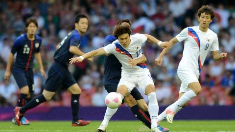 South Korean player Park Jongwoo, centre, fights for the ball with a Japanese player during the bronze medal football match on Friday. 