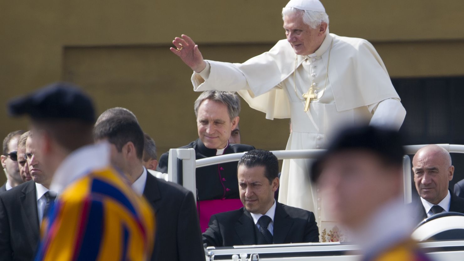 Pope Benedict XVI waves as he stands in his "popemobile" with his butler Paolo Gabriele, center seated.