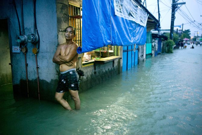 A man stands in a flooded street in Bulacan on Tuesday, August 14, as more rain falls on the region.