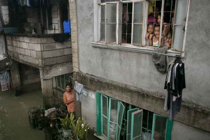Children look out from their home Tuesday as more rain falls in the flooded coastal region in Bulacan.