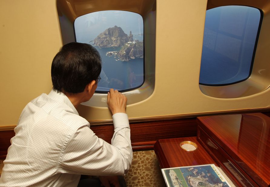 South Korean President Lee Myung-Bak points through the window of a helicopter at the remote islands disputed with Japan on August 10, 2012. It was the first visit by a South Korean president to the islands, which prompted Tokyo to recall its ambassador from Seoul in protest.
