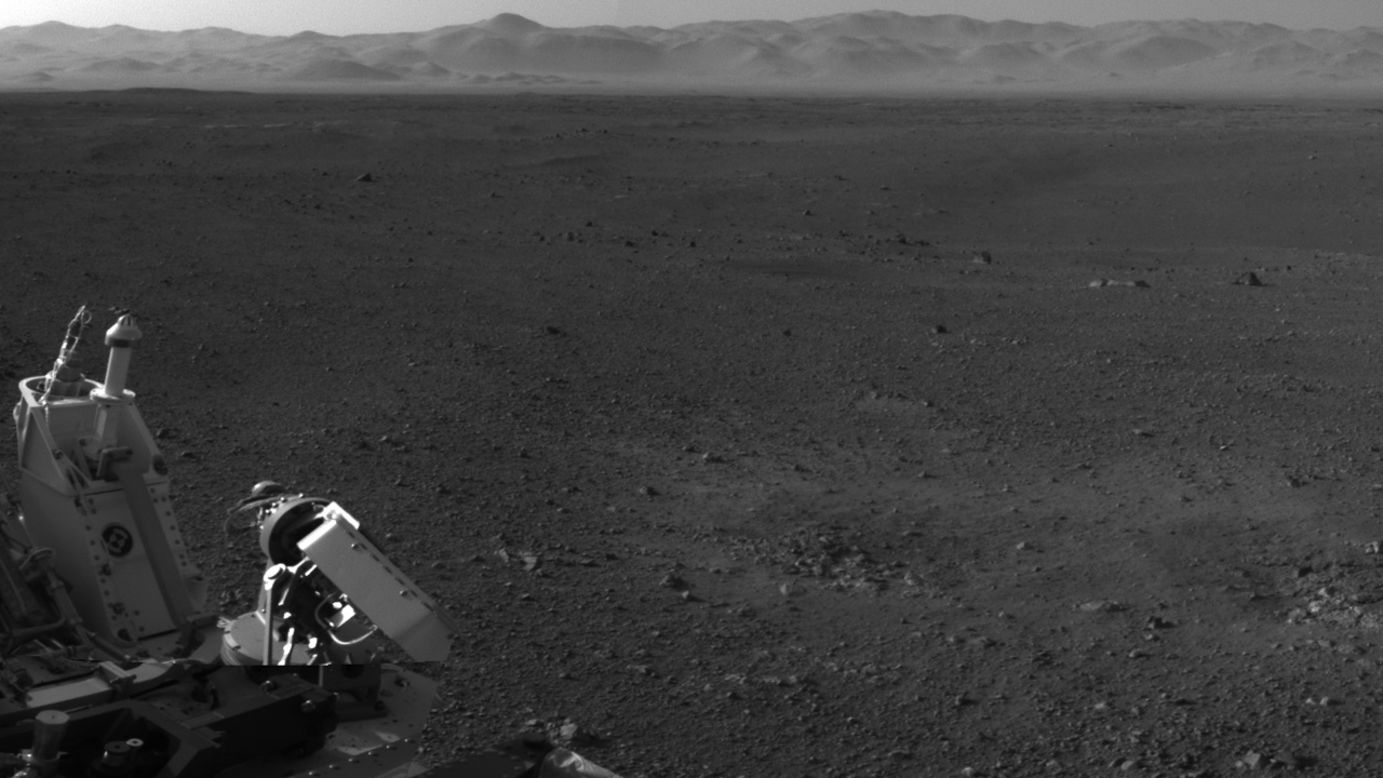 This image, with a portion of the rover in the corner, shows the wall of "Gale Crater" running across the horizon at the top of the image. 