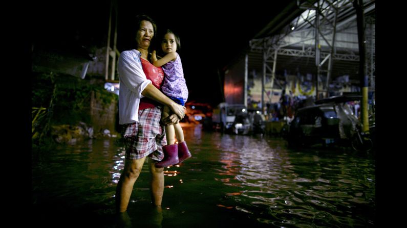 Precy Magtalas holds her daughter Kristine outside their home next to the Pampanga River. 