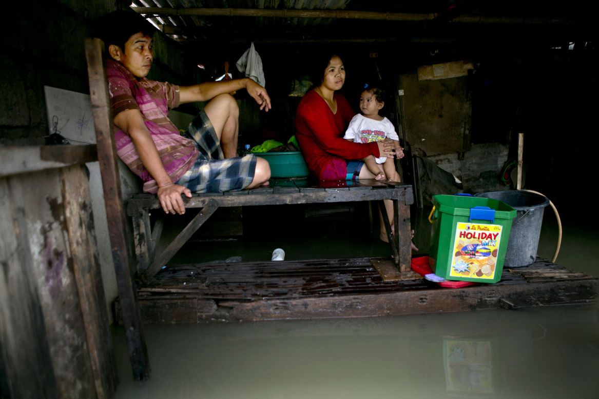 Leo Sampilay, his wife, Anna, and 1-year-old daughter, Kim, sit in their  home in a flooded province in Bulacan, Philippines. 
