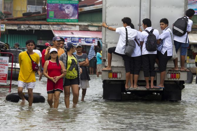 People walk along a flooded street as more rain falls in the flooded region on Tuesday, August 14,  in Bulacan.
