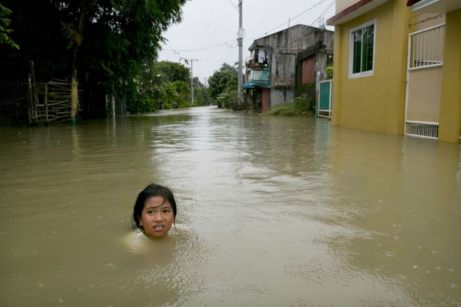  A girl is submerged in the water outside her home next to the swollen Pampanga River on Wednesday, August 15, in Bulacan, Philippines. 