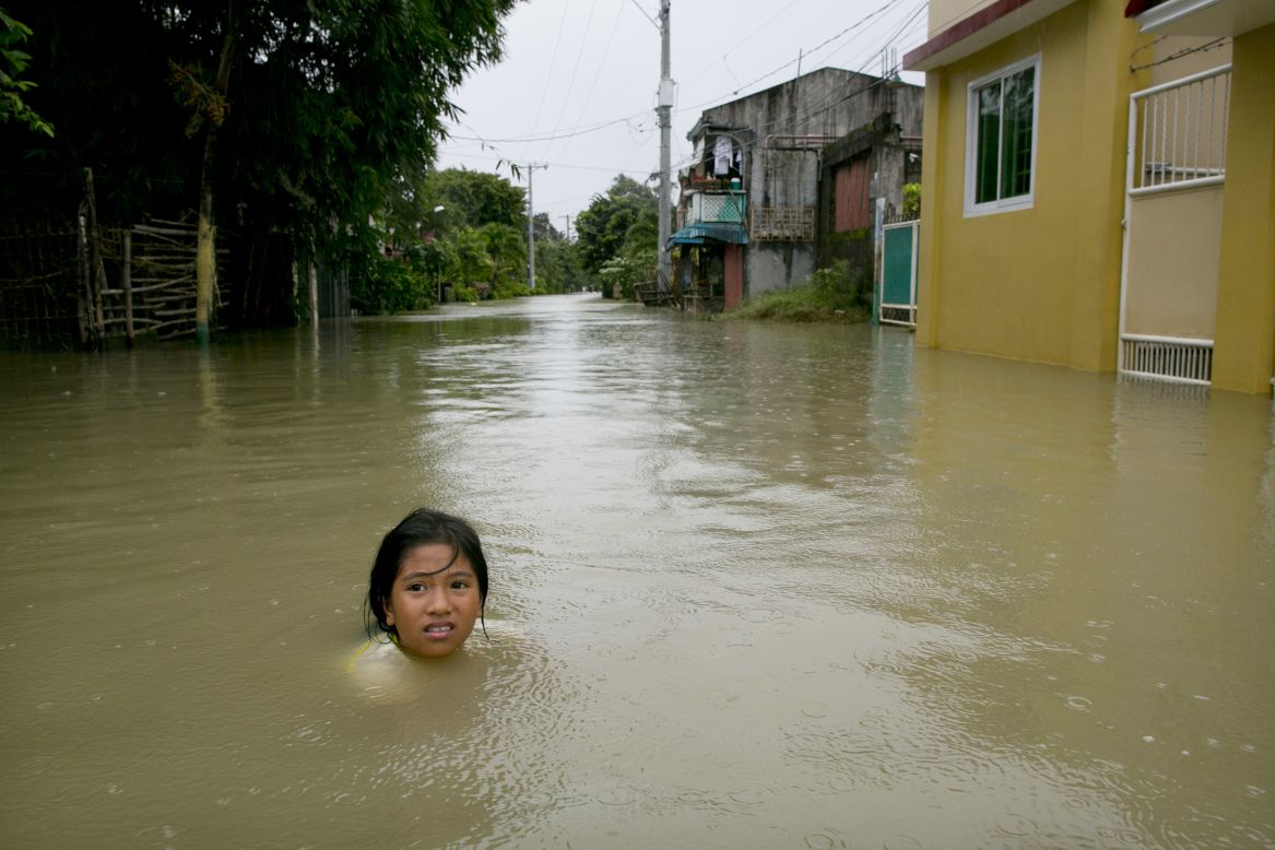  A girl is submerged in the water outside her home next to the swollen Pampanga River on Wednesday, August 15, in Bulacan, Philippines. 